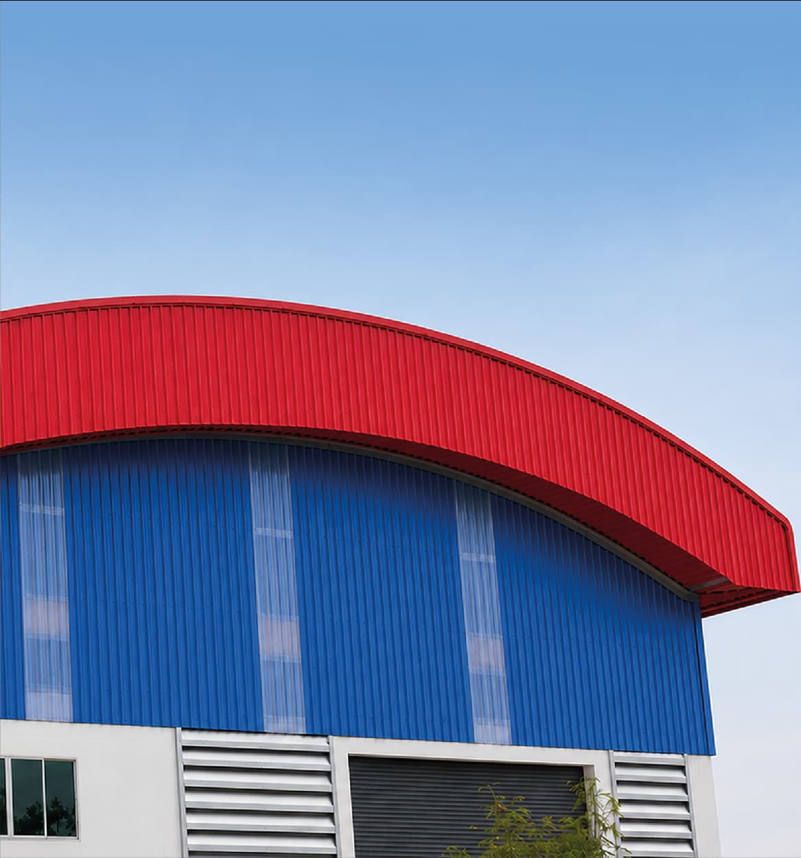 Industrial building with a curved red roof and blue profiled sheet cladding