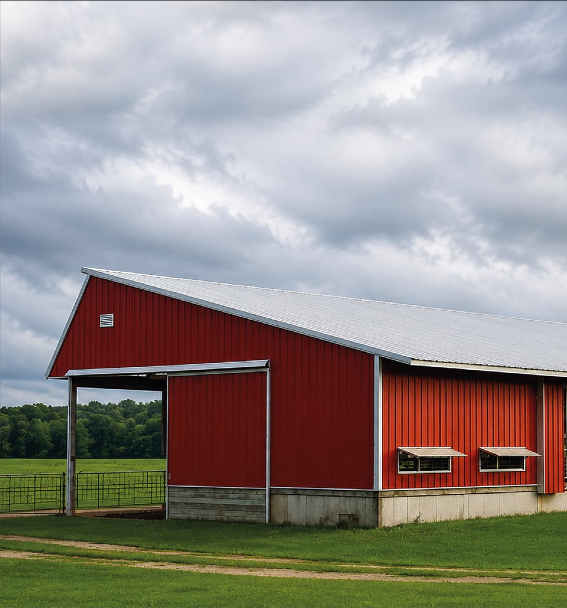 Farm shed clad in red sheets with a silver metal roof beside open fields